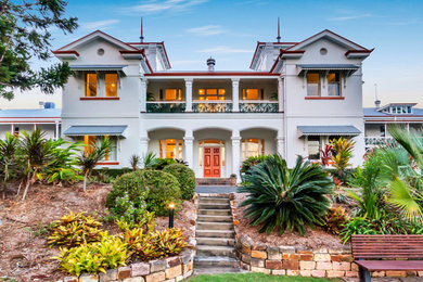 This is an example of a large and white victorian house exterior in Brisbane with four floors and a metal roof.