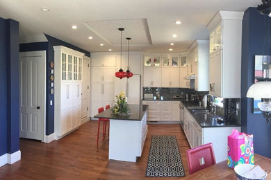 Mid-sized transitional u-shaped medium tone wood floor and brown floor eat-in kitchen photo in Chicago with shaker cabinets, white cabinets, quartz countertops, gray backsplash, glass tile backsplash, stainless steel appliances, an island and a double-bowl sink