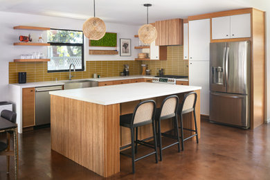 Inspiration for a large mid-century modern l-shaped concrete floor and brown floor open concept kitchen remodel in Los Angeles with a farmhouse sink, beaded inset cabinets, light wood cabinets, quartz countertops, green backsplash, porcelain backsplash, stainless steel appliances, an island and white countertops