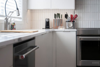Open concept kitchen - mid-sized modern l-shaped laminate floor and gray floor open concept kitchen idea in Other with an undermount sink, flat-panel cabinets, white cabinets, quartz countertops, white backsplash, porcelain backsplash, stainless steel appliances, an island and white countertops