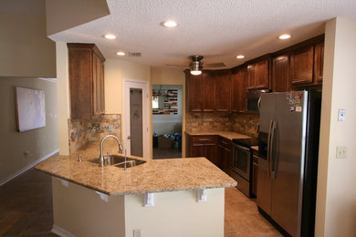 Eat-in kitchen - mid-sized transitional l-shaped porcelain tile eat-in kitchen idea in Jacksonville with an undermount sink, shaker cabinets, brown cabinets, granite countertops, beige backsplash, stone tile backsplash, stainless steel appliances and a peninsula