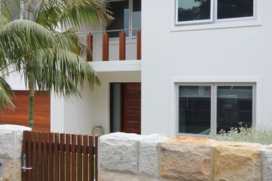 This is an example of a contemporary front door in Sydney with white walls, travertine floors, a pivot front door, a medium wood front door and beige floor.