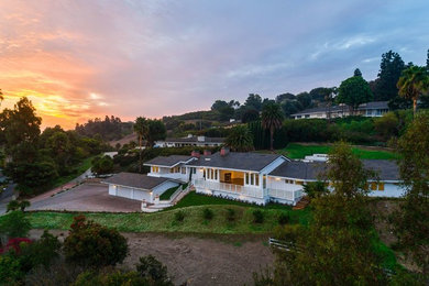 Example of a huge farmhouse white two-story board and batten house exterior design in Los Angeles