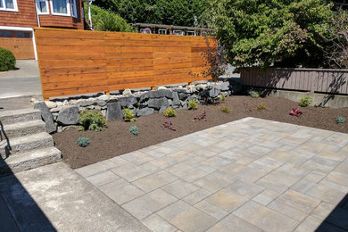 Photo of a mid-sized transitional drought-tolerant and full sun courtyard concrete paver retaining wall landscape in Seattle.