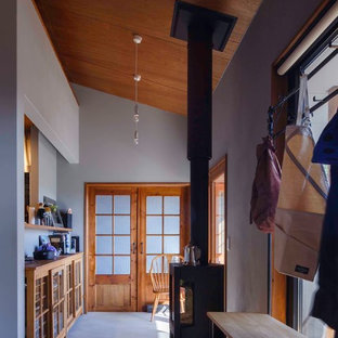 他の地域の中サイズの引き戸ラスティックスタイルのおしゃれな玄関ホール (グレーの壁、コンクリートの床、木目調のドア、グレーの床) の写真