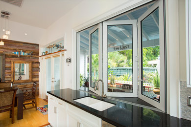 Inspiration for a mid-sized coastal galley ceramic tile eat-in kitchen remodel in Miami with a double-bowl sink, shaker cabinets, white cabinets, granite countertops, metallic backsplash, metal backsplash, stainless steel appliances and no island
