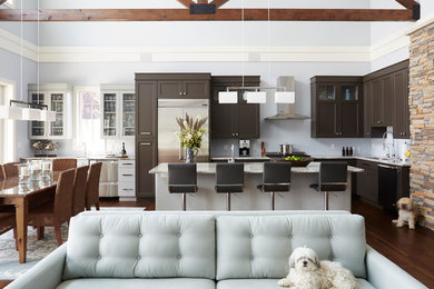 Inspiration for a transitional l-shaped dark wood floor open concept kitchen remodel in Milwaukee with an undermount sink, shaker cabinets, brown cabinets, stainless steel appliances and an island
