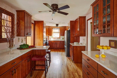 Mid-sized elegant galley light wood floor eat-in kitchen photo in Chicago with a double-bowl sink, raised-panel cabinets, medium tone wood cabinets, quartz countertops, brown backsplash, ceramic backsplash, stainless steel appliances and a peninsula