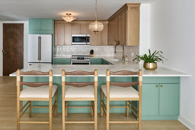 Example of a transitional u-shaped kitchen design in Chicago with recessed-panel cabinets, green cabinets, white backsplash, colored appliances, a peninsula and white countertops