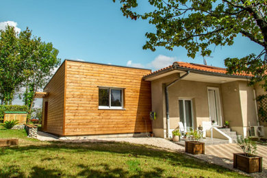 Aménagement d'une façade de maison moderne en bois et bardage à clin de taille moyenne et de plain-pied avec un toit plat, un toit mixte et un toit noir.