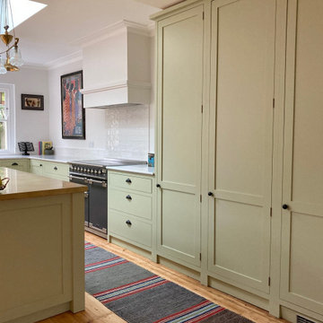 Light green cottage style kitchen with white worktops and kitchen island