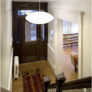 Eklektisk inredning av en liten ingång och ytterdörr, med vita väggar, ljust trägolv, en enkeldörr, mörk trädörr och beiget golv