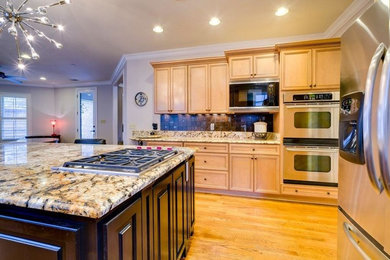 Example of a mid-sized transitional l-shaped eat-in kitchen design in Other with an undermount sink, recessed-panel cabinets, light wood cabinets, granite countertops, brown backsplash, stainless steel appliances and an island