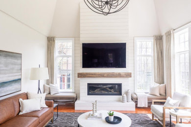 Example of a large transitional open concept medium tone wood floor family room design in Toronto with beige walls, a standard fireplace, a wood fireplace surround and a wall-mounted tv