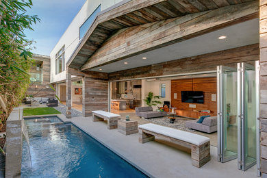 Mid-sized contemporary backyard rectangular pool in Los Angeles with a water feature and concrete slab.