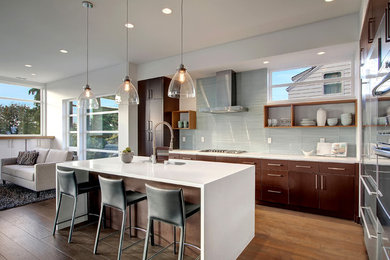 Design ideas for a large contemporary l-shaped open plan kitchen in Seattle with a single-bowl sink, flat-panel cabinets, dark wood cabinets, solid surface benchtops, blue splashback, porcelain splashback, stainless steel appliances, medium hardwood floors and with island.