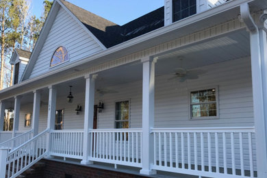 This is an example of a large traditional stone front porch design in Charleston with a roof extension.