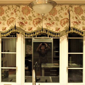Box pleat valances with a shaped hem and tassel trim in a green kitchen