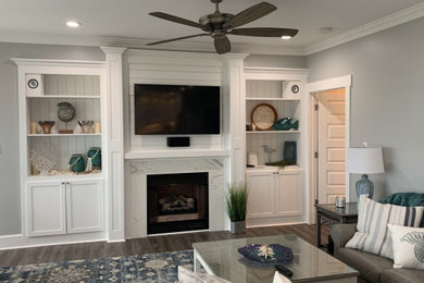 Example of a beach style gray floor living room design in Other with gray walls and a shiplap fireplace
