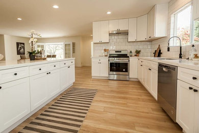 Inspiration for a mid-sized contemporary l-shaped open plan kitchen in San Luis Obispo with an undermount sink, shaker cabinets, white cabinets, quartz benchtops, white splashback, subway tile splashback, stainless steel appliances, light hardwood floors, with island, beige floor and white benchtop.