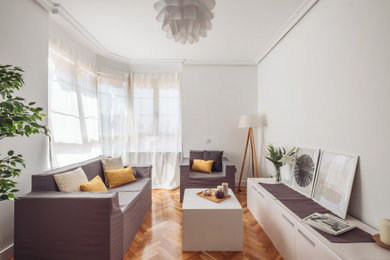Diseño de salón gris y blanco nórdico con paredes blancas, suelo de madera en tonos medios y suelo marrón