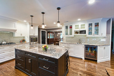 Inspiration for a large transitional u-shaped medium tone wood floor kitchen remodel in Philadelphia with recessed-panel cabinets, white cabinets, granite countertops, beige backsplash, subway tile backsplash, stainless steel appliances and an island