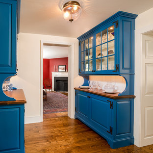 Réalisation d'une arrière-cuisine champêtre avec un placard à porte vitrée, des portes de placard bleues, un plan de travail en bois, une crédence blanche, un sol en bois brun et une crédence en bois.