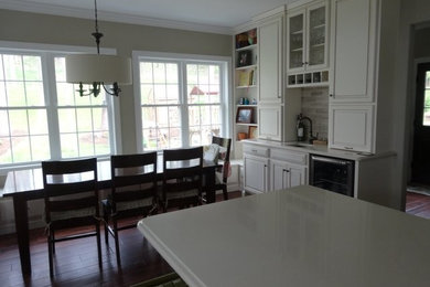 Example of a mid-sized classic l-shaped eat-in kitchen design in Other with raised-panel cabinets, white cabinets and an island