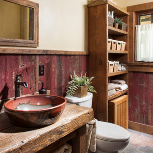 Inspiration for a small rustic concrete floor and red floor bathroom remodel in Other with open cabinets, brown cabinets, a two-piece toilet, beige walls, a vessel sink and wood countertops