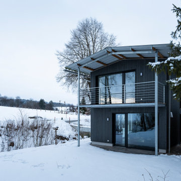 Schwarzes Einfamilienhaus in weißer Landschaft