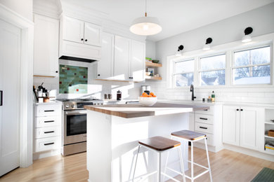 This is an example of a mid-sized transitional l-shaped eat-in kitchen in Minneapolis with an undermount sink, shaker cabinets, white cabinets, quartz benchtops, white splashback, subway tile splashback, stainless steel appliances, light hardwood floors, with island, brown floor, white benchtop and coffered.