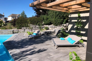 Pool fountain - large modern backyard concrete paver and l-shaped pool fountain idea in Ottawa