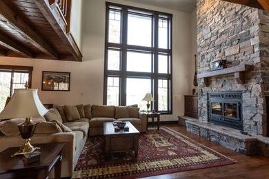 Mid-sized elegant open concept medium tone wood floor, brown floor and exposed beam living room photo in Other with white walls, a standard fireplace, a stone fireplace and no tv