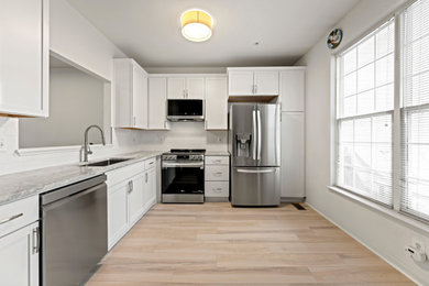 Example of a mid-sized classic l-shaped vinyl floor and beige floor enclosed kitchen design in DC Metro with an undermount sink, recessed-panel cabinets, white cabinets, granite countertops, white backsplash, ceramic backsplash, stainless steel appliances, no island and multicolored countertops