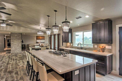 This is an example of a mid-sized industrial single-wall eat-in kitchen in Sacramento with a double-bowl sink, shaker cabinets, dark wood cabinets, beige splashback, stainless steel appliances, with island, multi-coloured floor, beige benchtop, granite benchtops and dark hardwood floors.