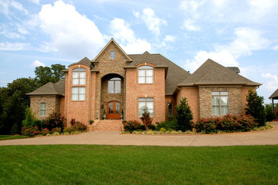 Large elegant brown two-story brick exterior home photo in Nashville with a shingle roof