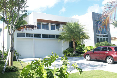 This is an example of a contemporary two-storey white house exterior in Miami with a flat roof.