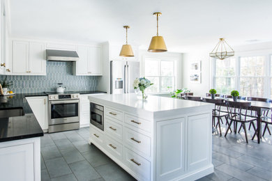 Inredning av ett klassiskt mellanstort vit vitt kök, med en undermonterad diskho, skåp i shakerstil, vita skåp, bänkskiva i kvarts, blått stänkskydd, stänkskydd i porslinskakel, rostfria vitvaror, klinkergolv i porslin, en köksö och grått golv