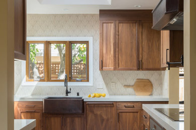 Example of a mid-sized tuscan u-shaped medium tone wood floor, brown floor and vaulted ceiling eat-in kitchen design in San Francisco with a farmhouse sink, flat-panel cabinets, brown cabinets, quartz countertops, beige backsplash, stone tile backsplash, paneled appliances, no island and beige countertops