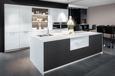 This is an example of a mid-sized modern galley eat-in kitchen in Christchurch with a double-bowl sink, flat-panel cabinets, white cabinets, laminate benchtops, stainless steel appliances and with island.