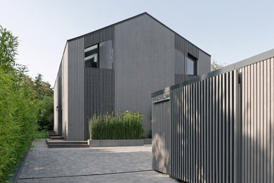 Modelo de fachada de casa gris y gris actual grande de tres plantas con revestimiento de madera, tejado a dos aguas, tejado de metal y tablilla
