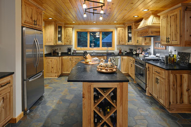 Example of a mountain style u-shaped kitchen design in Other with shaker cabinets, medium tone wood cabinets, stainless steel appliances and an island