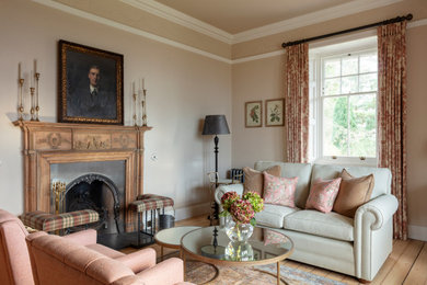 Inspiration for a classic living room in Edinburgh with beige walls, medium hardwood flooring, a standard fireplace and brown floors.