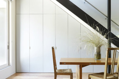 Contemporary dining room in Sydney with white walls and light hardwood floors.