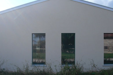 На фото: маленький, одноэтажный, белый дом в стиле модернизм с комбинированной облицовкой и двускатной крышей для на участке и в саду с