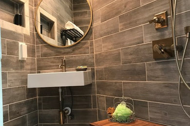 Example of a small minimalist master brown tile and ceramic tile ceramic tile and beige floor wet room design in Other with a two-piece toilet, brown walls, a wall-mount sink and a hinged shower door