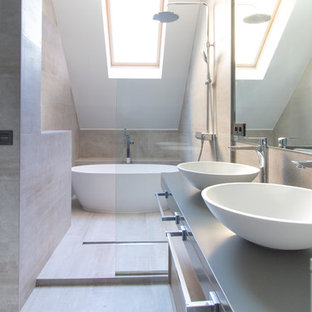 Cette image montre une salle de bain principale design de taille moyenne avec une baignoire indépendante, une vasque, un espace douche bain, un carrelage beige, un mur beige, un plan de toilette en acier inoxydable, un sol beige et aucune cabine.