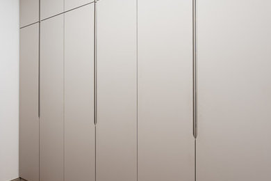 This is an example of a large contemporary gender-neutral walk-in wardrobe in Paris with beaded inset cabinets, grey cabinets and light hardwood floors.