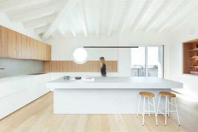 This is an example of a large contemporary l-shaped separate kitchen in Venice with flat-panel cabinets, white cabinets, wood benchtops, grey splashback, black appliances, dark hardwood floors, with island, brown floor and white benchtop.