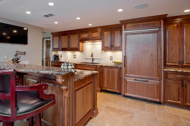Large elegant l-shaped ceramic tile and beige floor eat-in kitchen photo with raised-panel cabinets, dark wood cabinets, marble countertops, paneled appliances, a peninsula, an undermount sink and beige backsplash